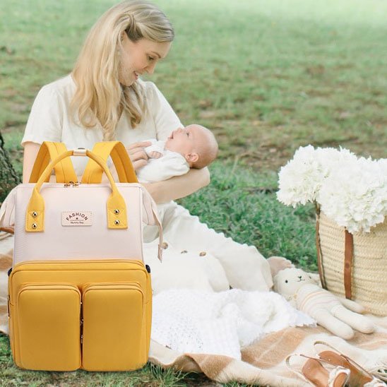 Sac a langer, couleur blanc jaune maman assise sur un gazon.