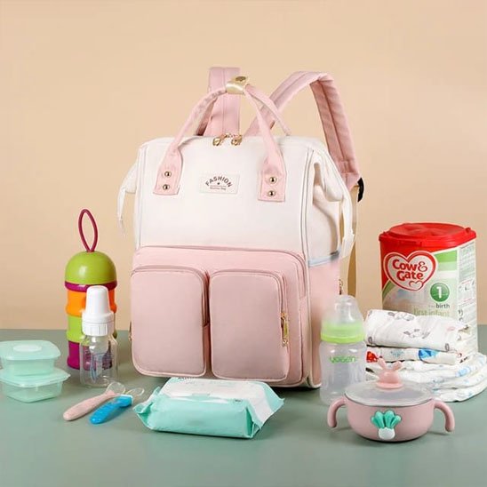 Sac a langer, couleur blanc rose avec les éléments à mettre dans le sac autour du sac.